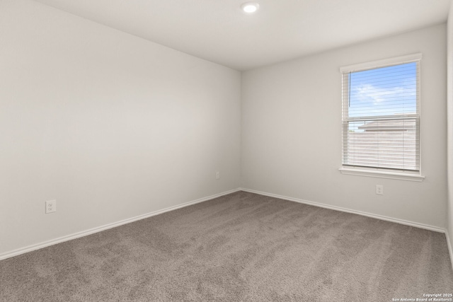 spare room featuring carpet flooring and baseboards