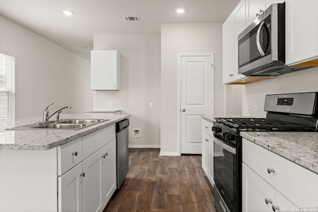 kitchen with dark wood-style floors, stainless steel appliances, visible vents, a sink, and light stone countertops