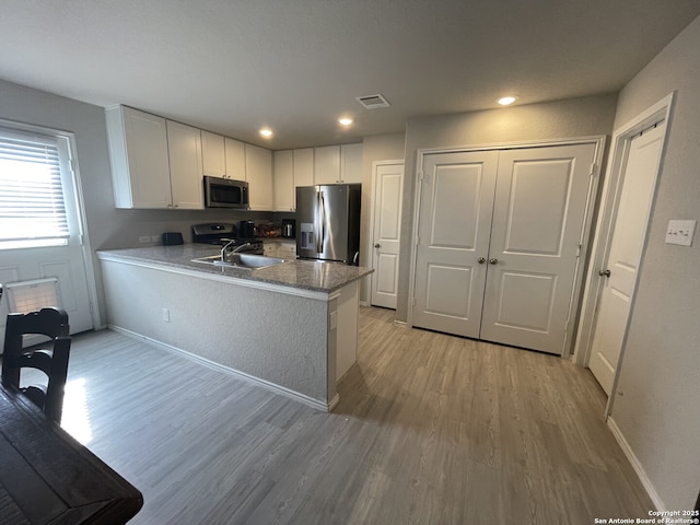 kitchen featuring appliances with stainless steel finishes, light wood-style flooring, visible vents, and white cabinetry