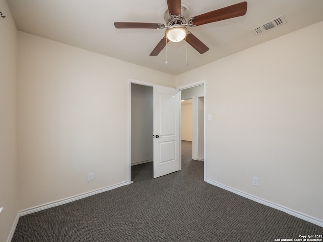 unfurnished bedroom with visible vents, dark carpet, baseboards, and ceiling fan