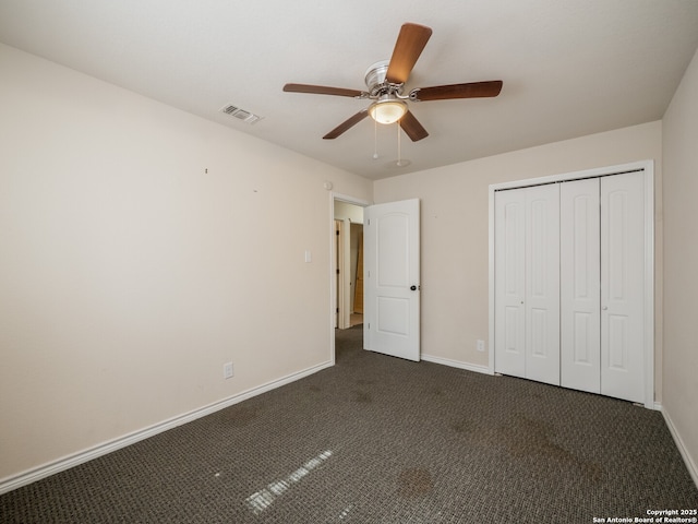 unfurnished bedroom with dark colored carpet, a closet, visible vents, and baseboards