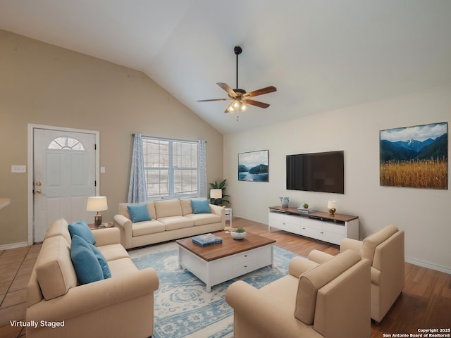 living area with high vaulted ceiling, ceiling fan, light wood-style flooring, and baseboards