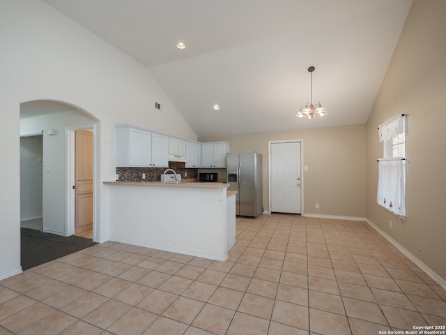 kitchen featuring arched walkways, white cabinets, stainless steel fridge with ice dispenser, a peninsula, and a notable chandelier