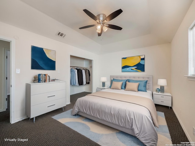 carpeted bedroom with ceiling fan, visible vents, baseboards, a spacious closet, and a tray ceiling