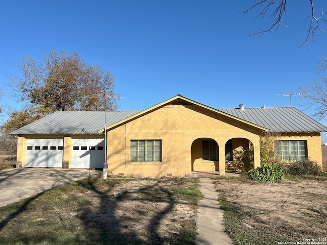 view of front of house featuring a garage, metal roof, concrete driveway, and brick siding