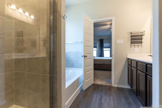 ensuite bathroom with a garden tub, a shower stall, connected bathroom, and wood finished floors