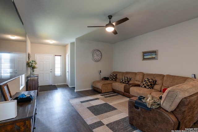 living area with a wealth of natural light, dark wood-style flooring, ceiling fan, and baseboards