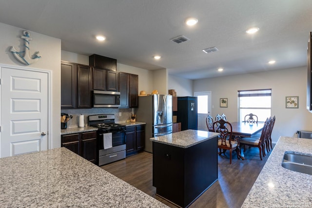 kitchen with visible vents, a kitchen island, appliances with stainless steel finishes, and dark wood-style flooring