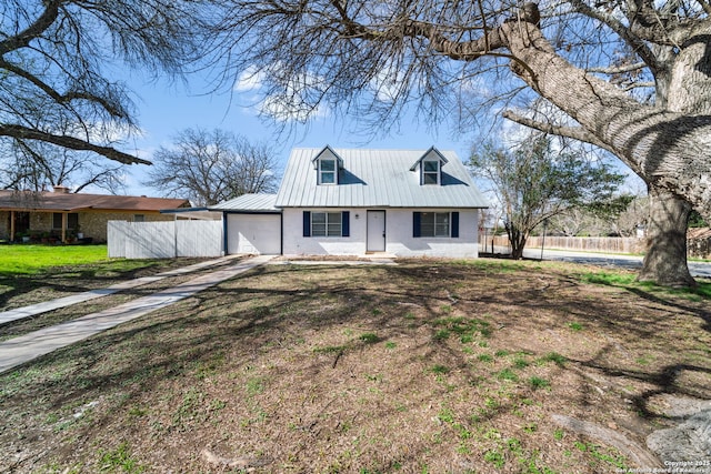 view of front of property with driveway, brick siding, metal roof, fence, and a front yard