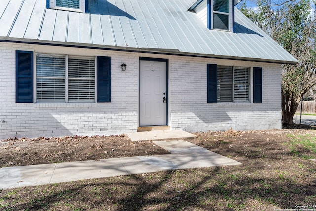 entrance to property featuring a standing seam roof, brick siding, and metal roof