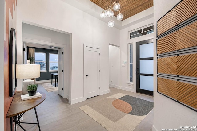 entrance foyer featuring wood finished floors, wooden ceiling, baseboards, and an inviting chandelier