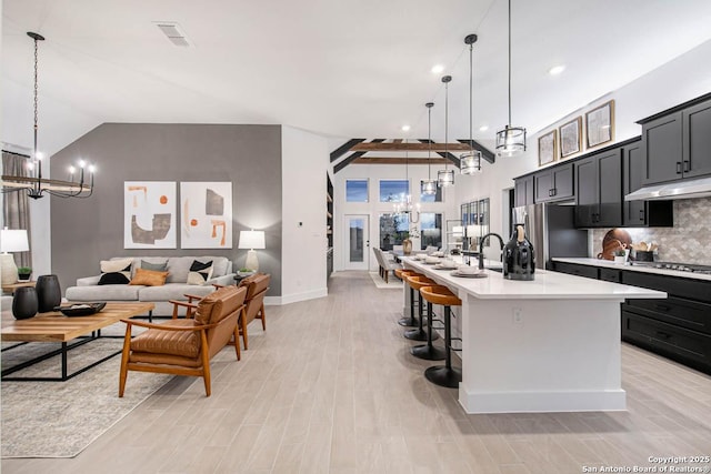 kitchen with appliances with stainless steel finishes, open floor plan, a notable chandelier, light countertops, and backsplash