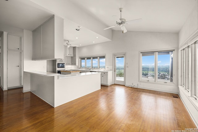 kitchen with a peninsula, visible vents, a ceiling fan, and wood finished floors