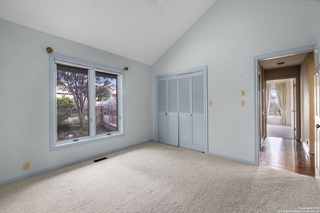 unfurnished bedroom featuring high vaulted ceiling, visible vents, baseboards, a closet, and carpet