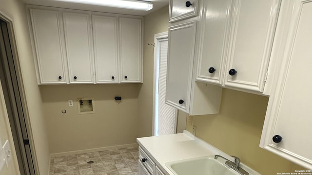 clothes washing area with cabinet space, baseboards, washer hookup, and a sink