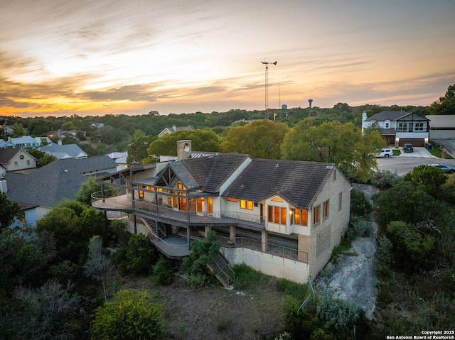 back of property at dusk featuring a tile roof and a chimney