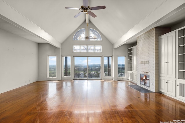 unfurnished living room with ceiling fan, high vaulted ceiling, hardwood / wood-style flooring, built in features, and a brick fireplace