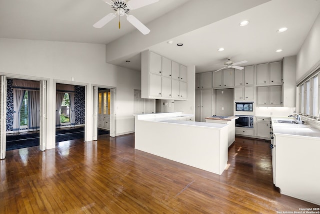 kitchen with wall oven, black microwave, dark wood finished floors, and a ceiling fan