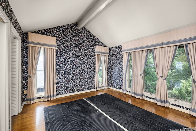 spare room with wood finished floors, vaulted ceiling with beams, baseboards, and wallpapered walls