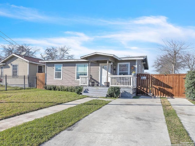 view of front of property with a front yard, covered porch, fence, and driveway