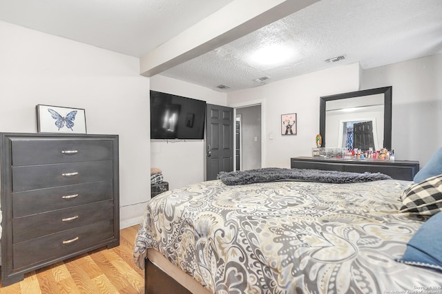 bedroom featuring visible vents, a textured ceiling, and light wood finished floors