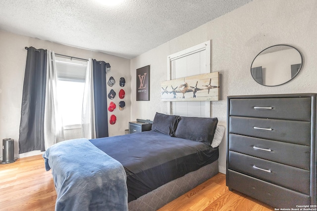 bedroom with a textured wall, a textured ceiling, and wood finished floors