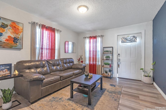 living area with a textured ceiling, light wood-style flooring, and baseboards