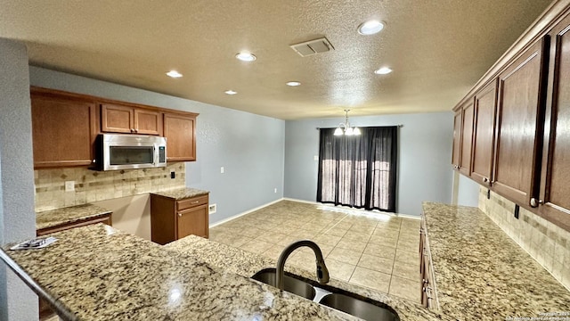 915 Ridingate Farm, San Antonio, TX 78228 - kitchen with backsplash, stainless steel microwave, a sink, and visible vents