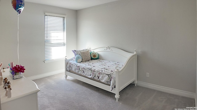 carpeted bedroom featuring multiple windows and baseboards