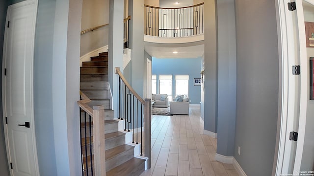 foyer entrance with stairs, a high ceiling, baseboards, and wood finished floors