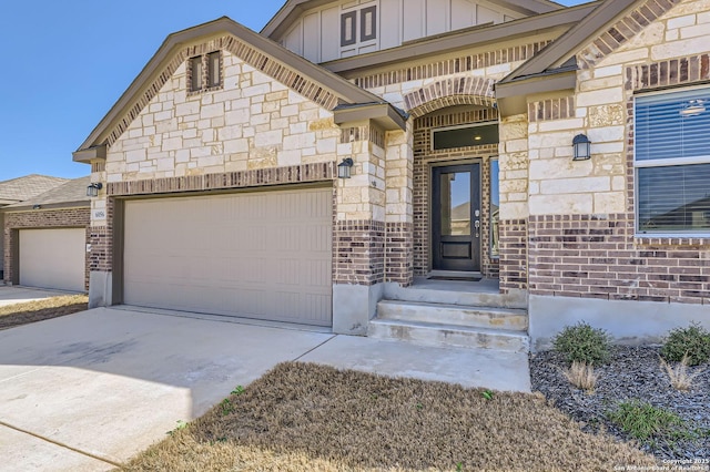 property entrance featuring board and batten siding, brick siding, driveway, and a garage