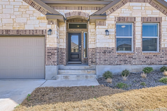 doorway to property with stone siding, brick siding, and an attached garage