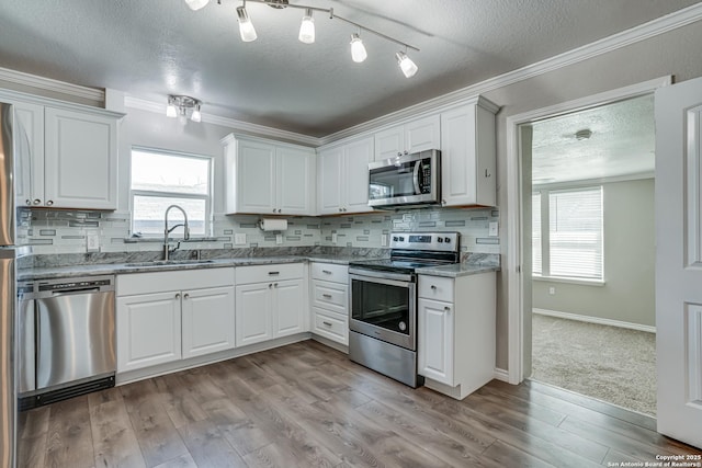 kitchen featuring appliances with stainless steel finishes, white cabinets, a sink, and tasteful backsplash