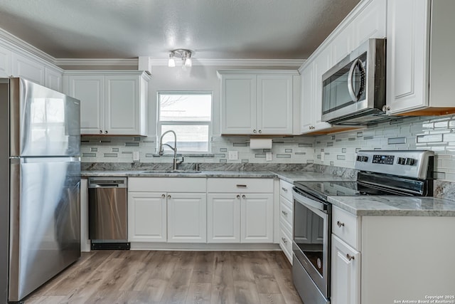 kitchen with stainless steel appliances, light wood-style flooring, a sink, and white cabinetry