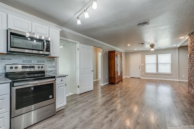 kitchen with ceiling fan, white cabinetry, appliances with stainless steel finishes, light wood-type flooring, and tasteful backsplash