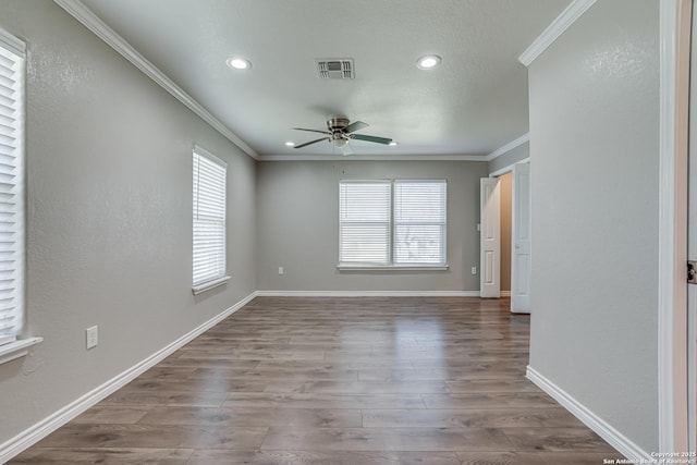 spare room featuring crown molding, visible vents, a ceiling fan, wood finished floors, and baseboards