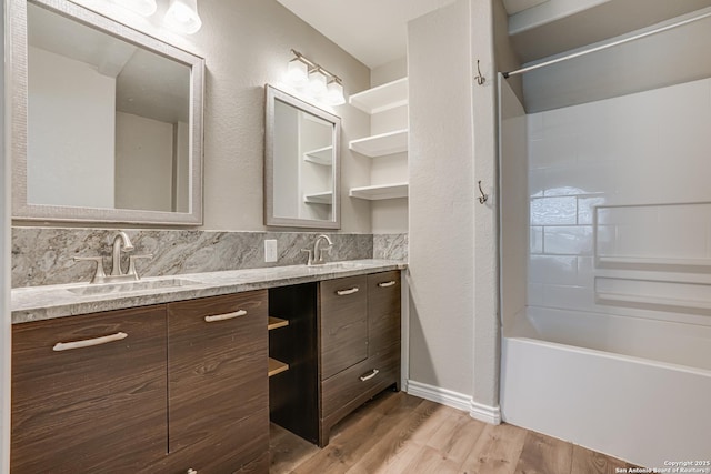 full bathroom featuring double vanity, wood finished floors, a sink, and  shower combination