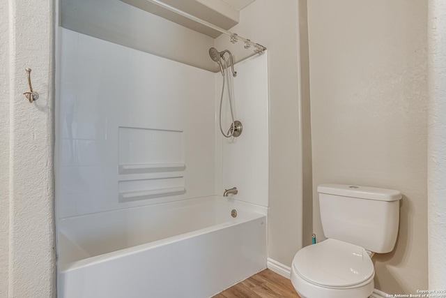 bathroom with bathing tub / shower combination, toilet, and wood finished floors