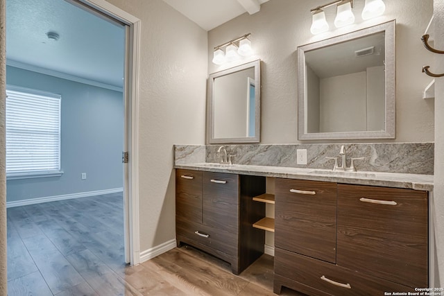 bathroom featuring double vanity, visible vents, wood finished floors, crown molding, and a sink