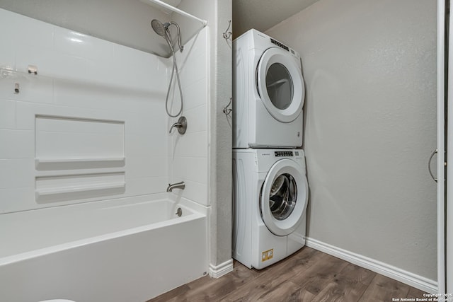 laundry room with stacked washer / dryer, laundry area, baseboards, and dark wood-style flooring