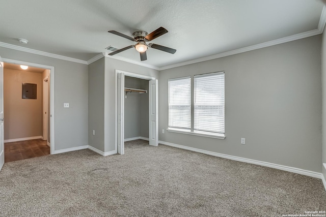 unfurnished bedroom featuring electric panel, baseboards, ornamental molding, carpet floors, and a closet