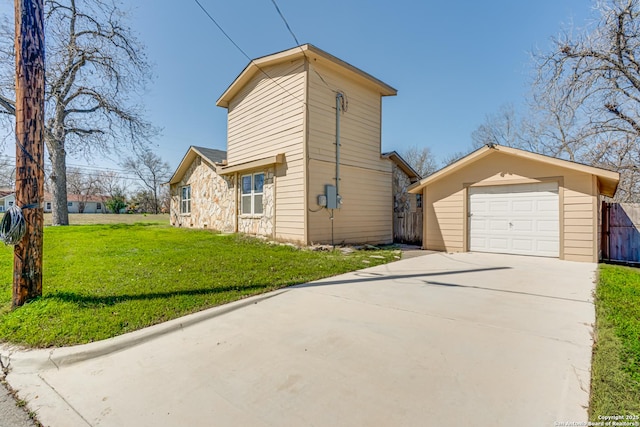 view of home's exterior with an outbuilding, concrete driveway, a lawn, and fence