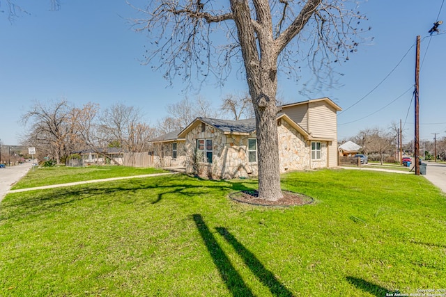 view of front of property featuring stone siding, a front yard, and fence