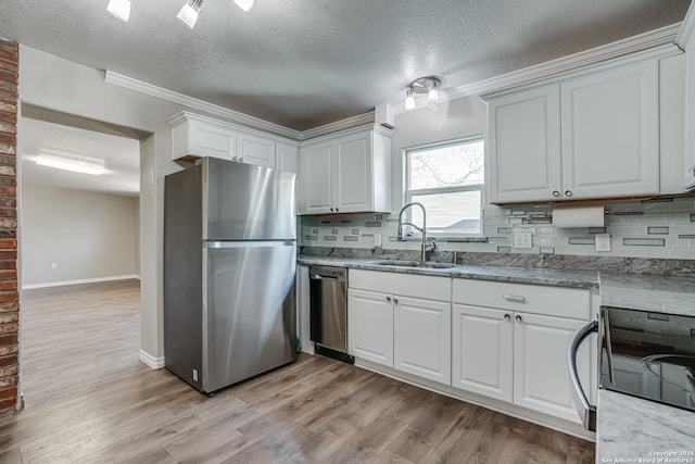 kitchen with light wood-style floors, appliances with stainless steel finishes, white cabinets, and a sink