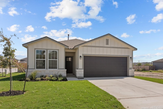 view of front facade featuring a garage, driveway, fence, board and batten siding, and a front yard