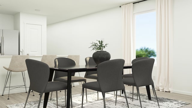 dining room featuring baseboards, plenty of natural light, and light wood-style floors