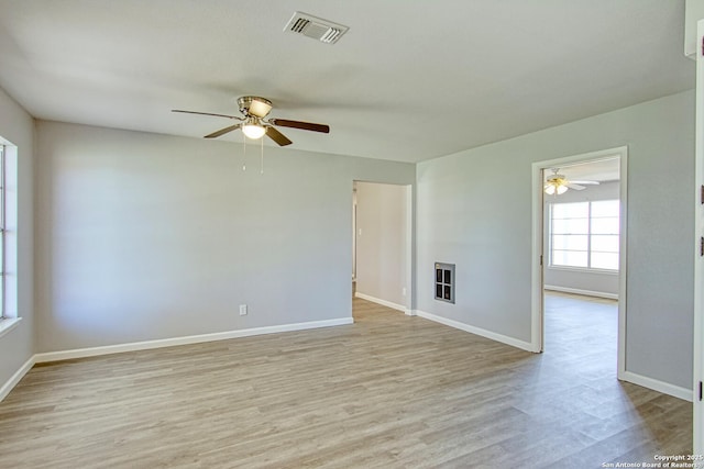 spare room with ceiling fan, light wood-type flooring, visible vents, and baseboards