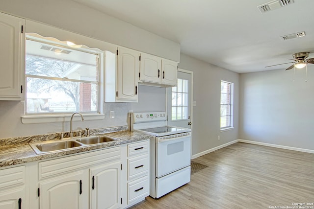 kitchen with a wealth of natural light, white electric range, a sink, and visible vents