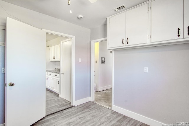 clothes washing area with light wood-style flooring, visible vents, and baseboards