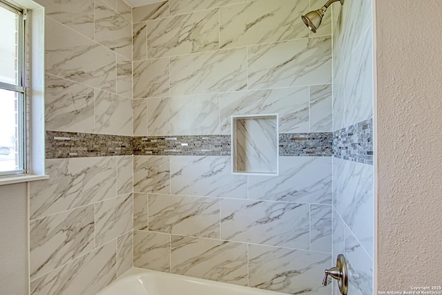 bathroom featuring washtub / shower combination and a textured wall